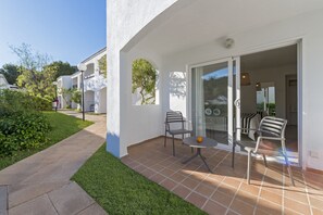 A patio area with two chairs and a table, a glass door leading to an interior space, and a small garden area with a pathway. - FERGUS Club Europa (Calvia)
