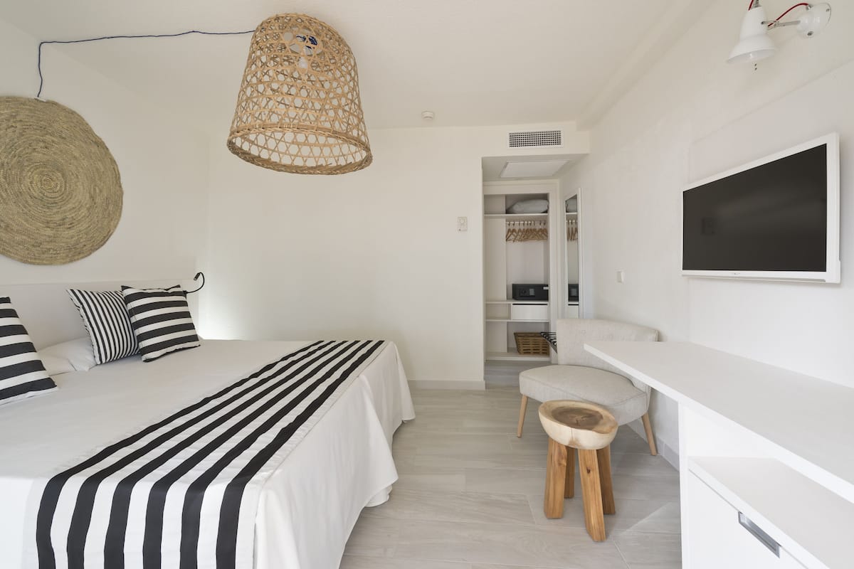 A bedroom with a bed, bedside table, and a hanging light fixture.