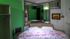 Une chambre à coucher avec un lit, un miroir, une table de chevet et un mur vert.