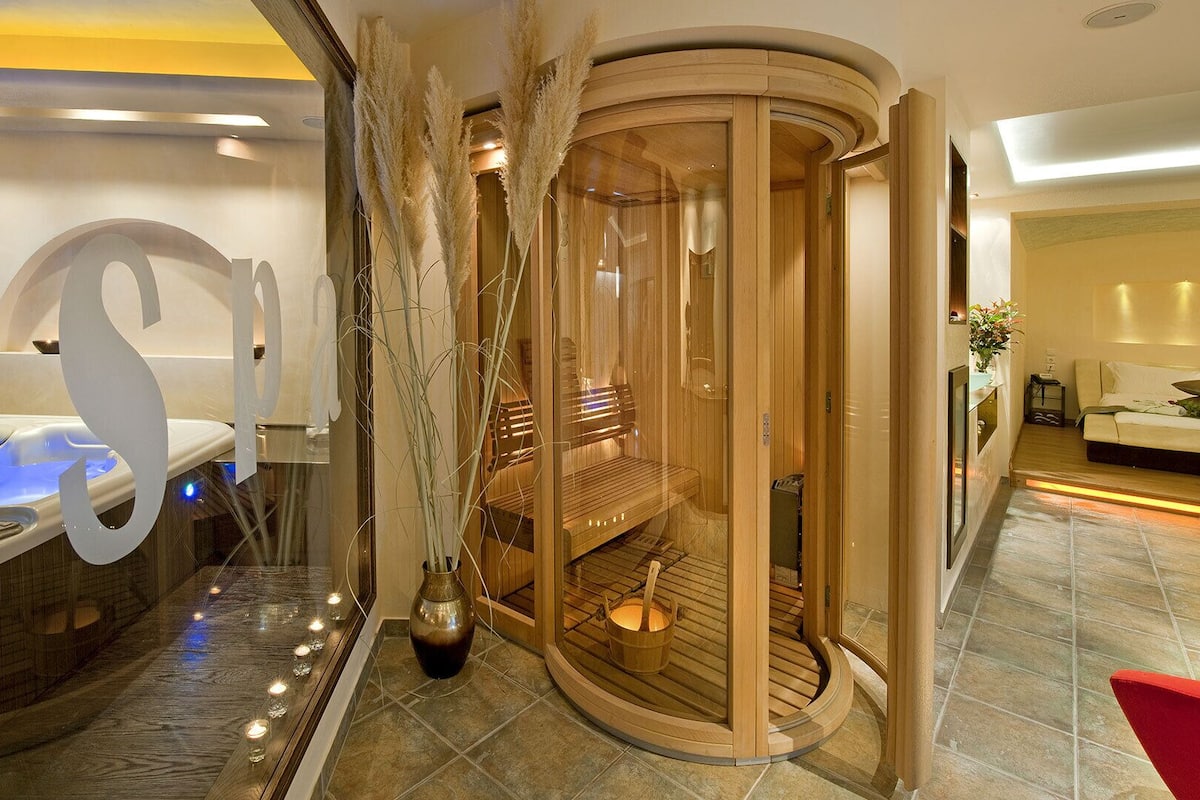 A modern spa room with a hot tub, a sauna, and a wooden cabinet.