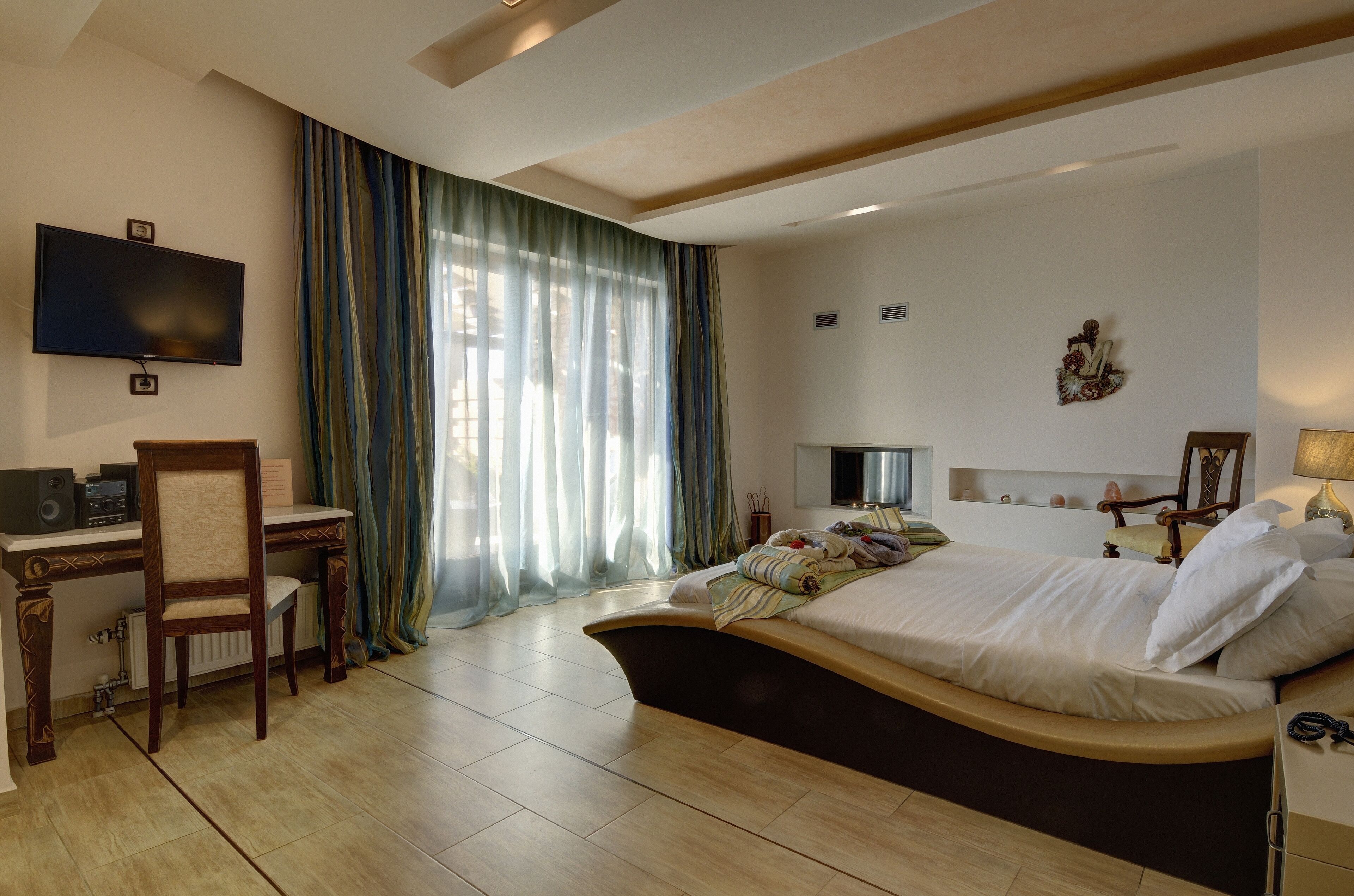 Une chambre d’hôtel avec un lit, un bureau, une télévision et une fenêtre avec des rideaux.