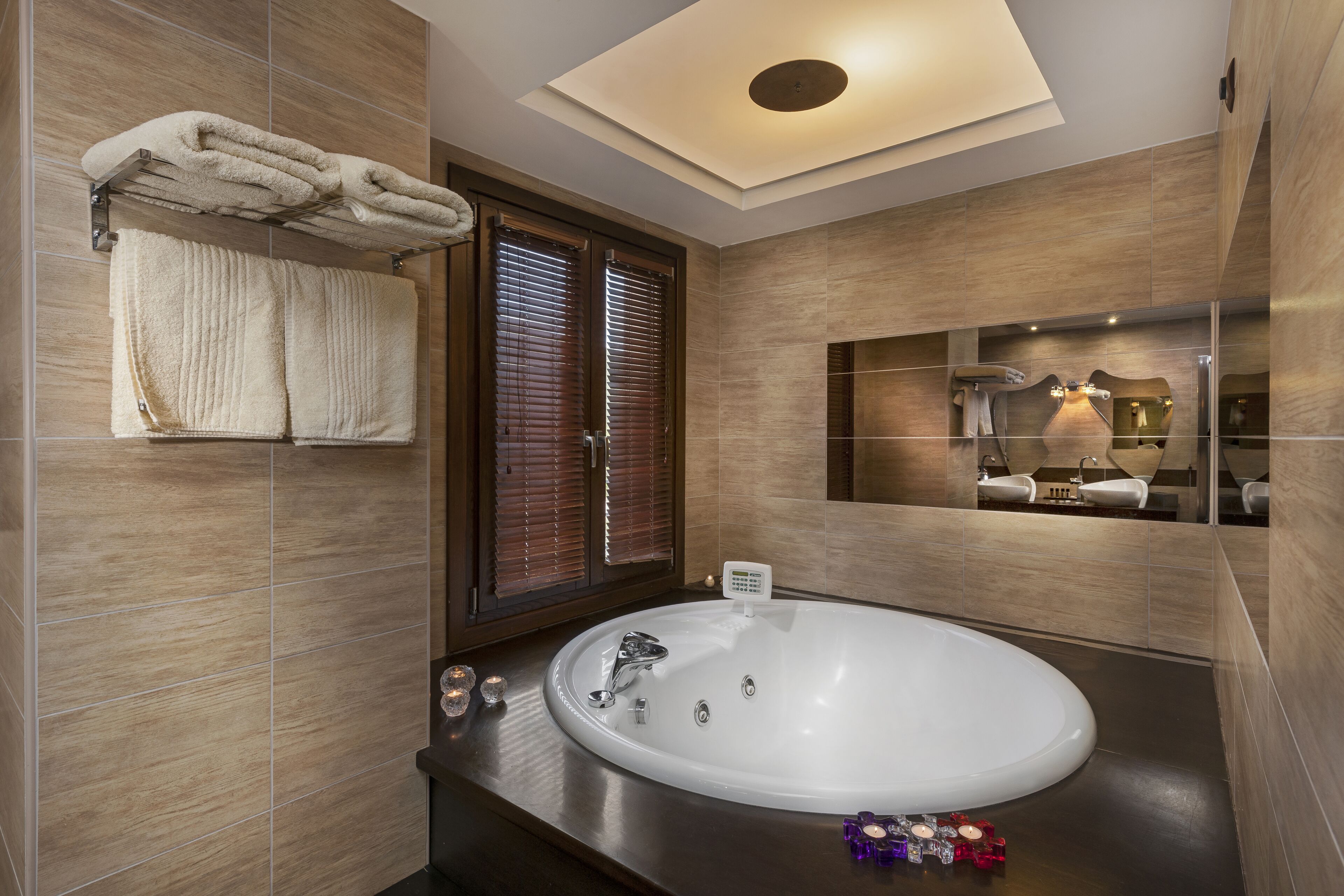 Un baño moderno con una bañera grande, persianas de madera y un espejo que refleja el baño.