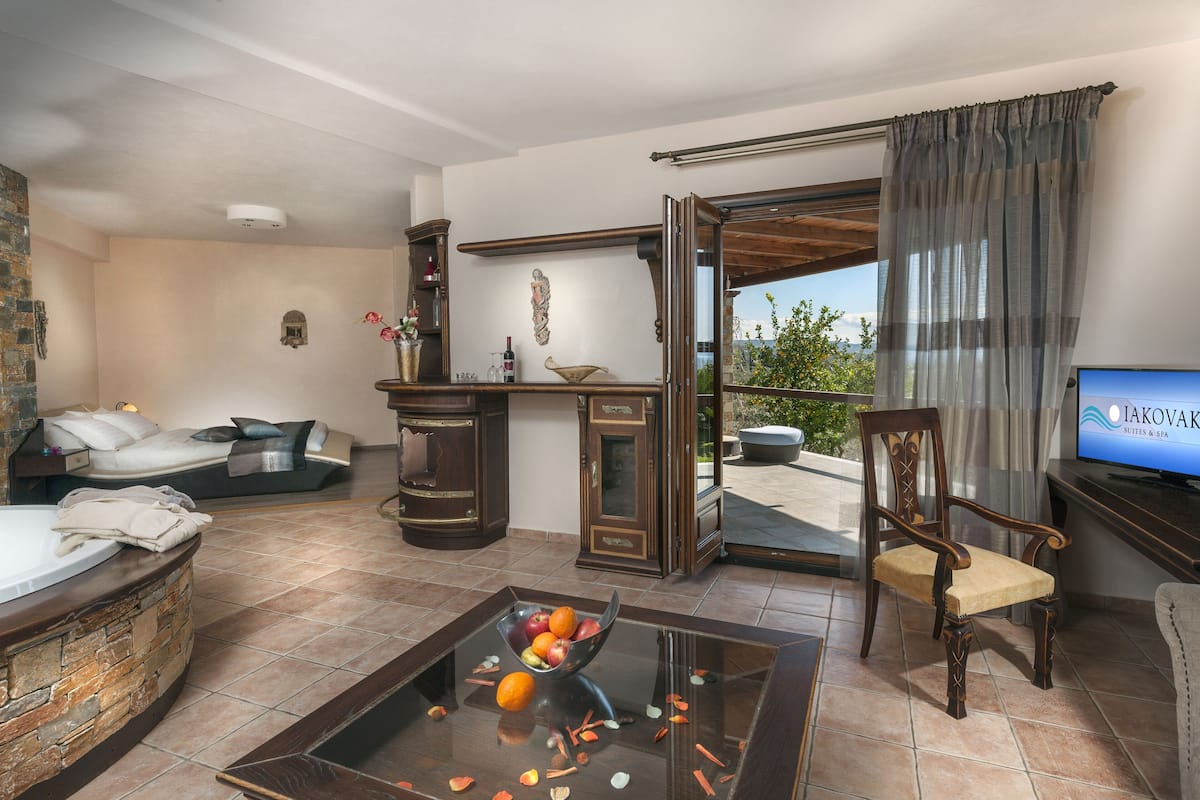 A spacious living area with a large window, a sofa, a coffee table with fruit, and a television.