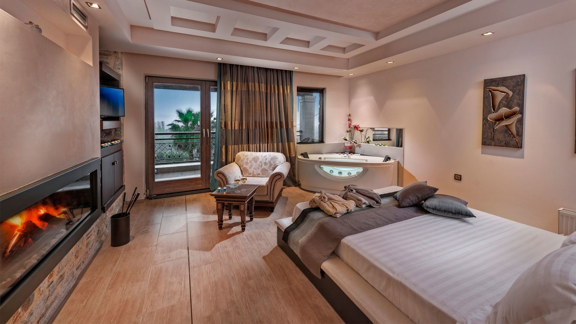 A modern hotel room with a fireplace, a sofa, a bed, a bathroom with a bathtub, and a balcony with a view.