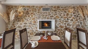 A dining area with a stone wall, a fireplace, and two chairs.