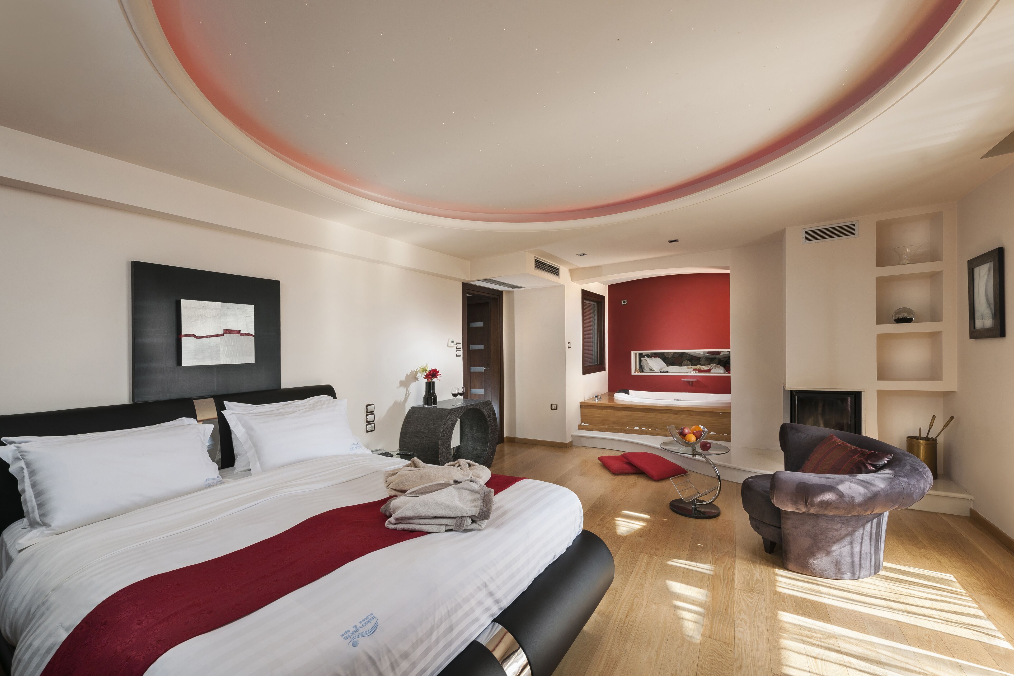 Een moderne hotelkamer met een groot bed, een zithoek met een rode bank en een kleine tafel met een bloemenvaas.