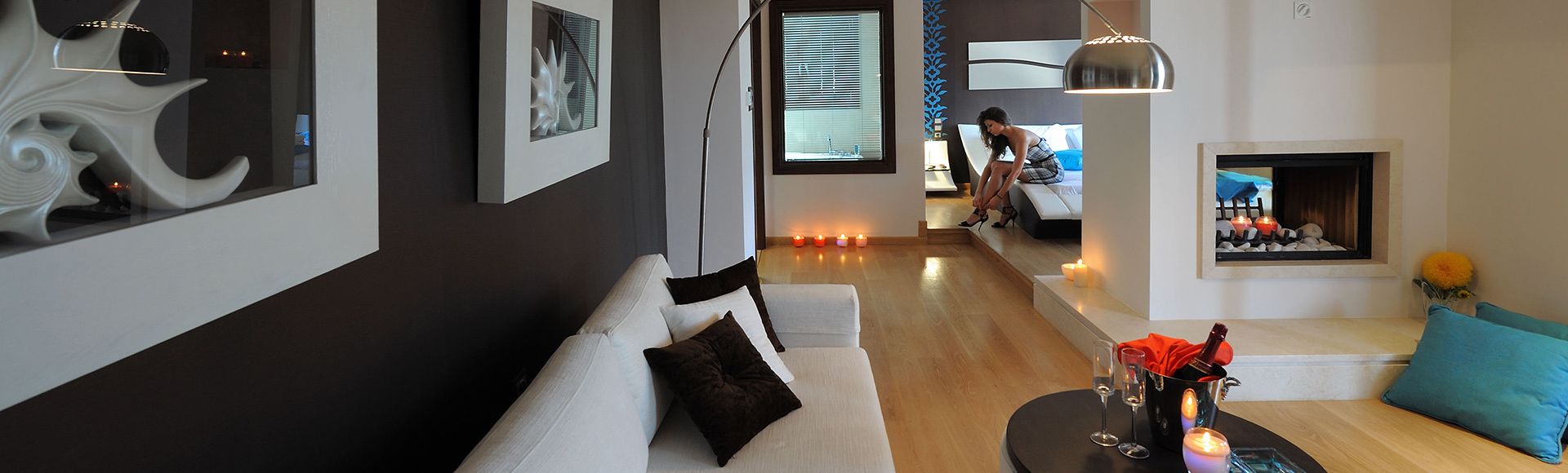 A modern living room with a sofa, a coffee table with drinks, and a fireplace.