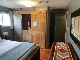 Un dormitorio con cama, una puerta de madera, un baño y un mapa en la pared.