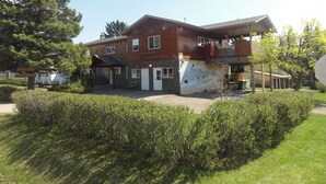 A two-story building with a stone facade, a balcony, and a mural on the side. - Smithers Guesthouse (Smithers)