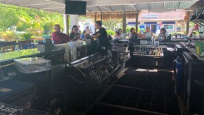 Zona de bar al aire libre con mostrador, taburetes y ventilador de techo.