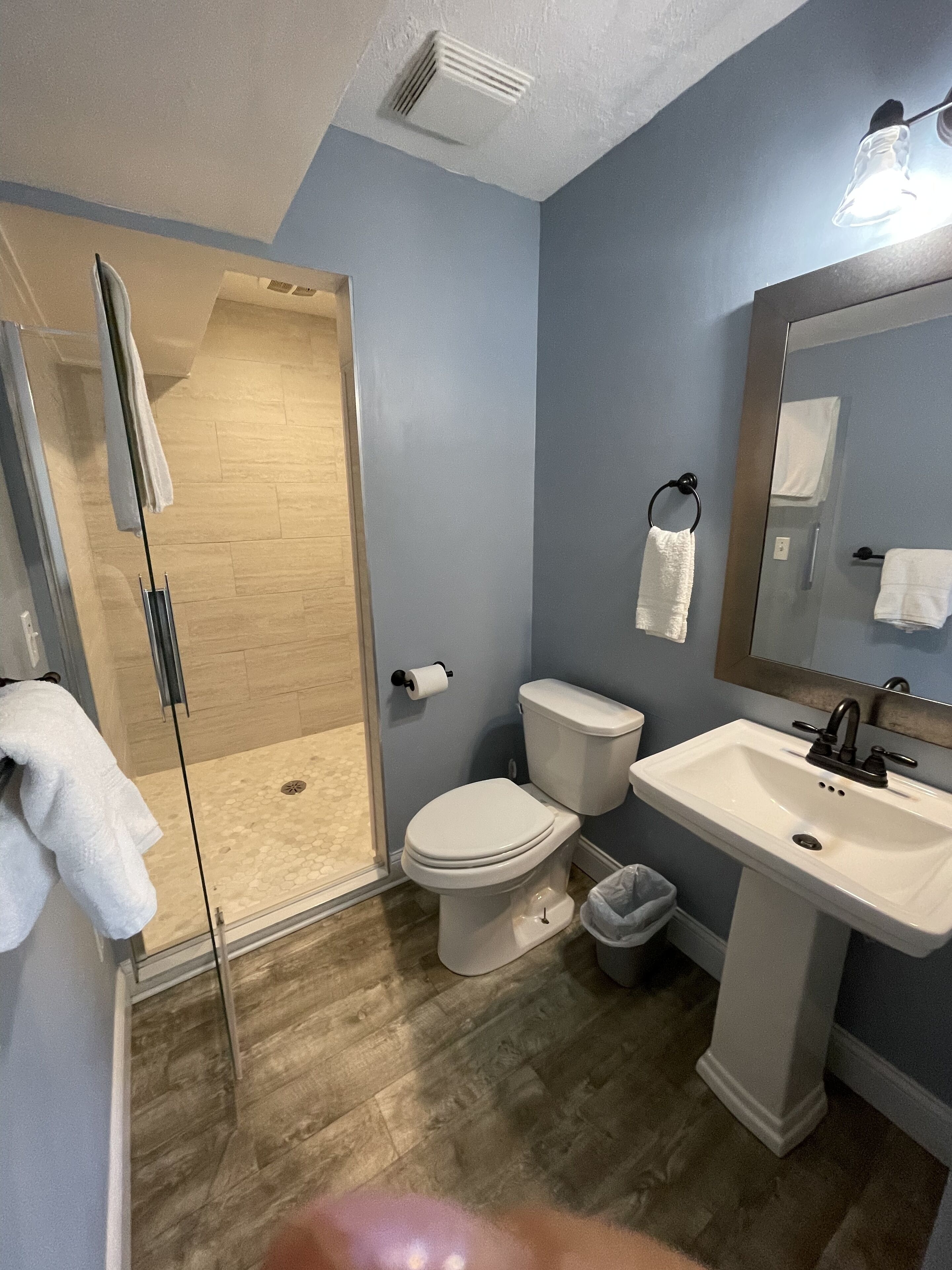 Un baño con cabina de ducha de vidrio, inodoro, lavabo y espejo.