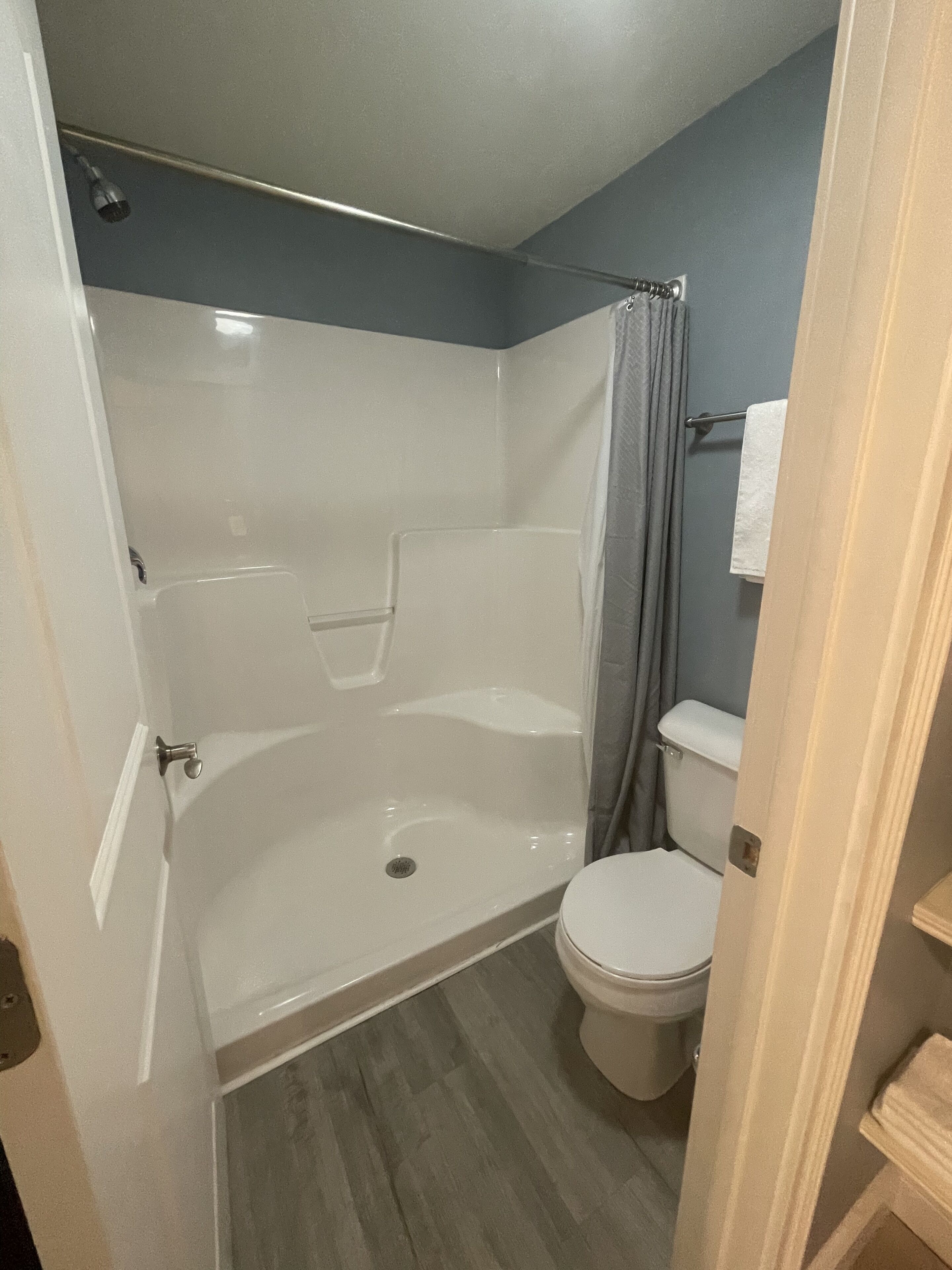 A bathroom with a shower, toilet, and a towel rack.