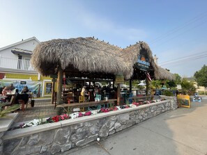 A restaurant with a thatched roof, outdoor seating, and a stone wall with flowers. - Harbour Square Suites (Put-in-Bay)
