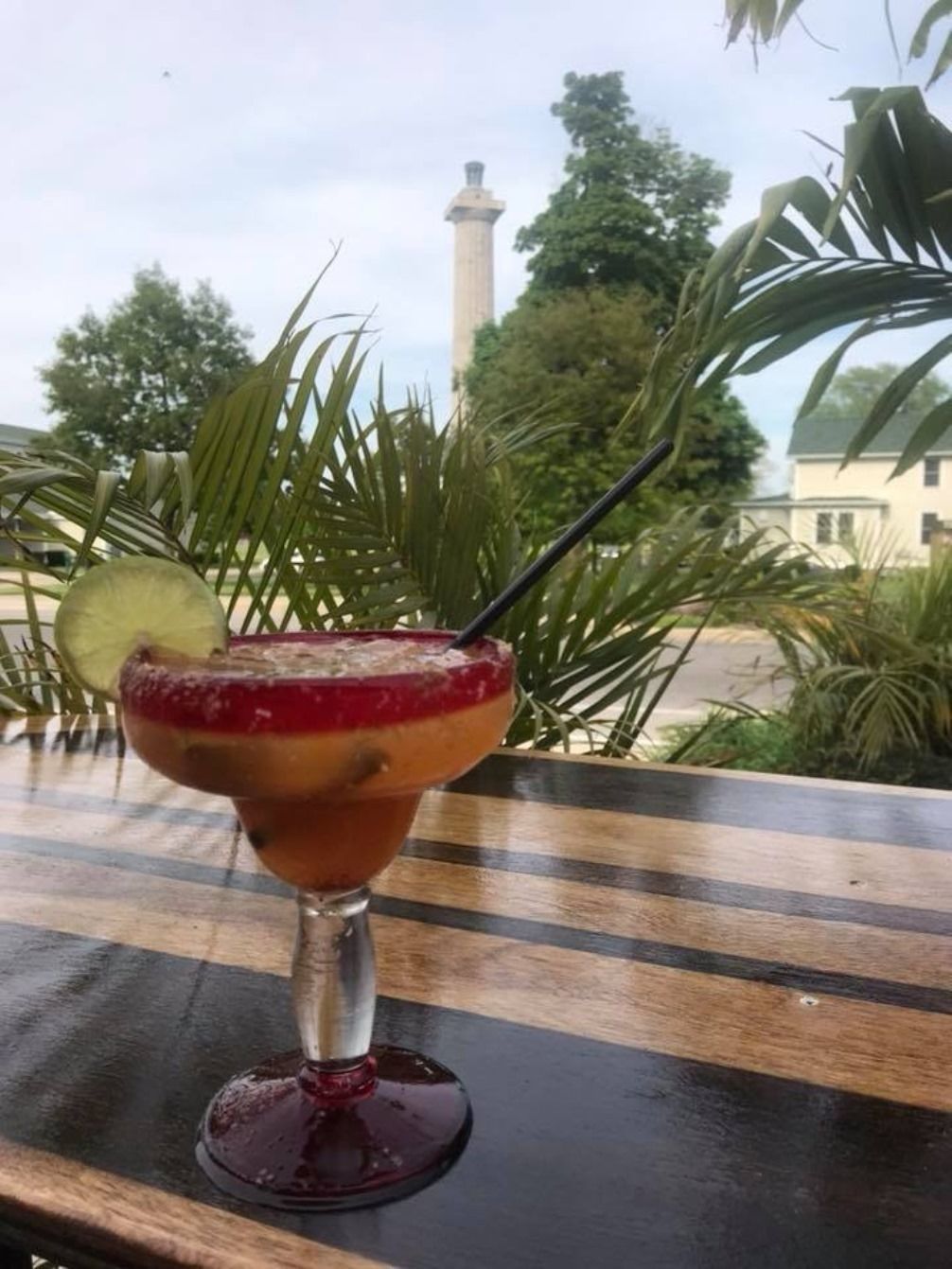 A cocktail on a table with a view of a lighthouse in the background.