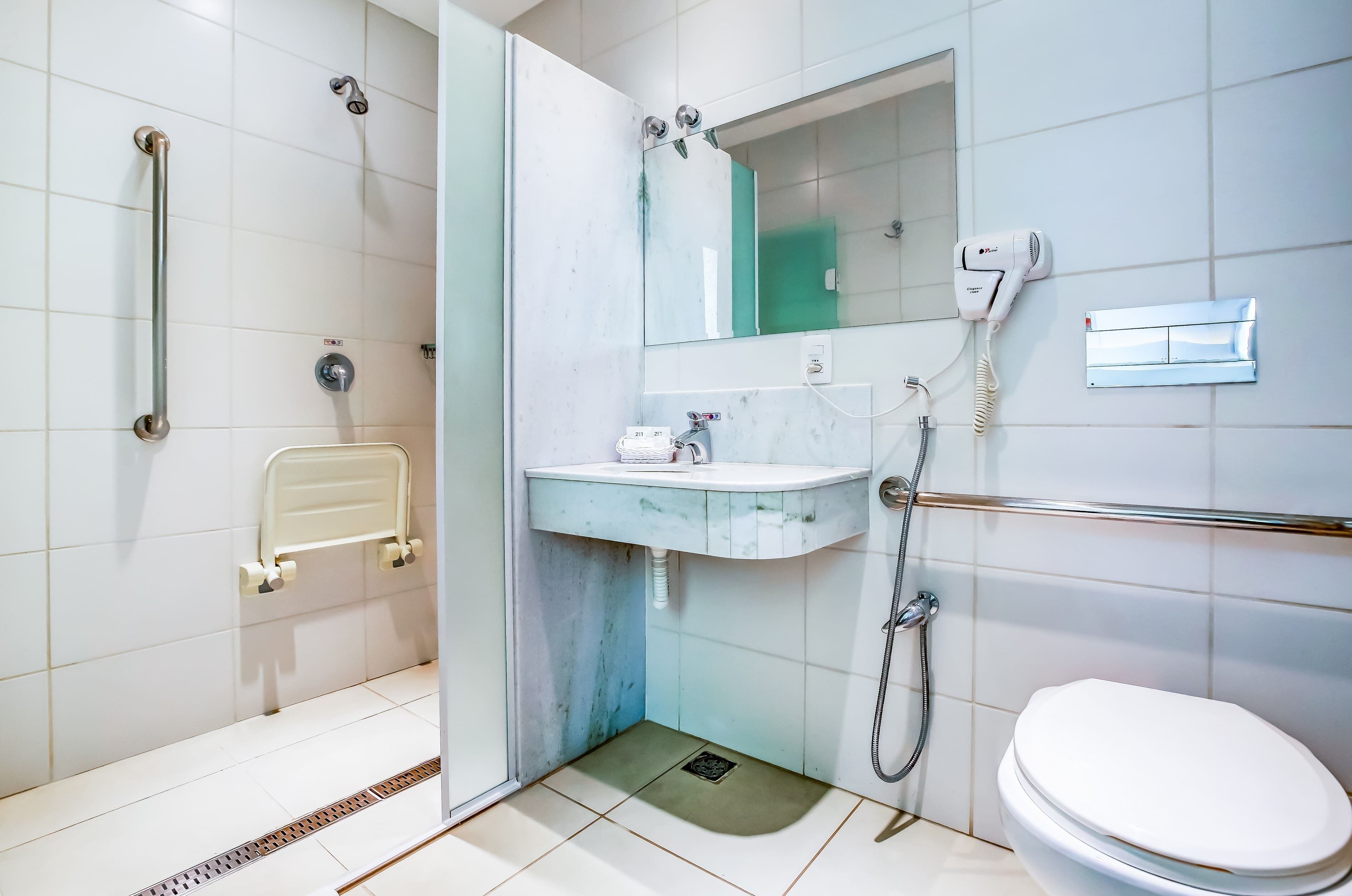 Een moderne badkamer met douche, toilet en wastafel.