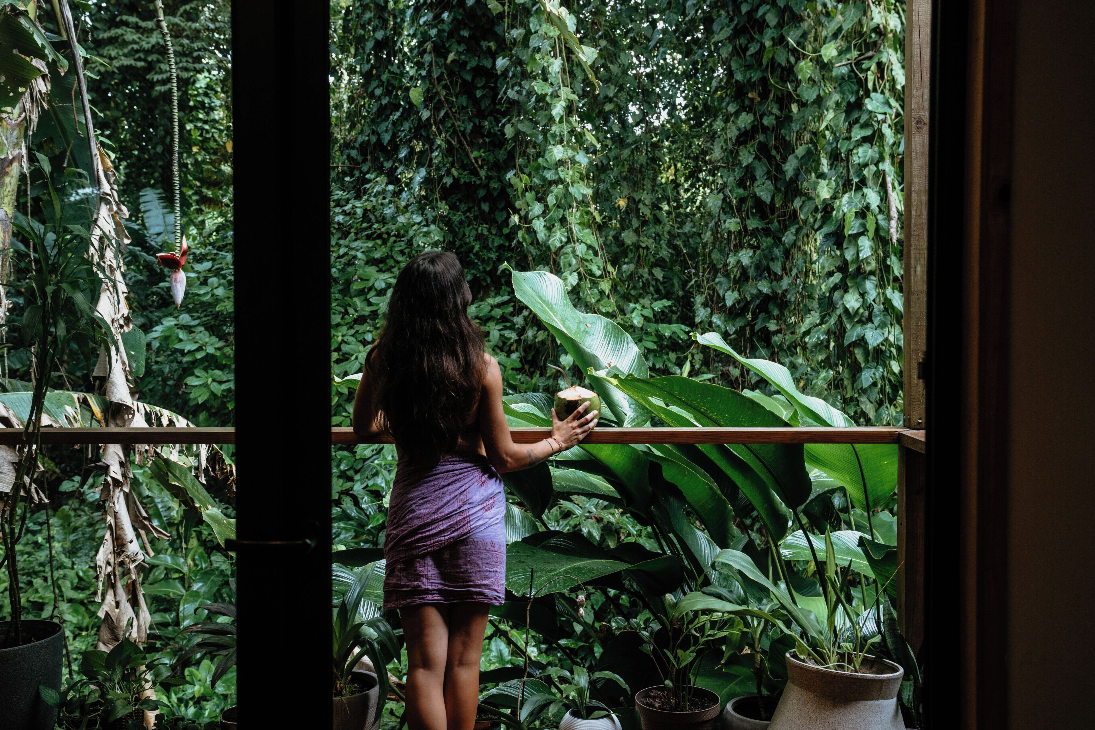 Una persona de pie cerca de un balcón con vista a una vegetación densa.