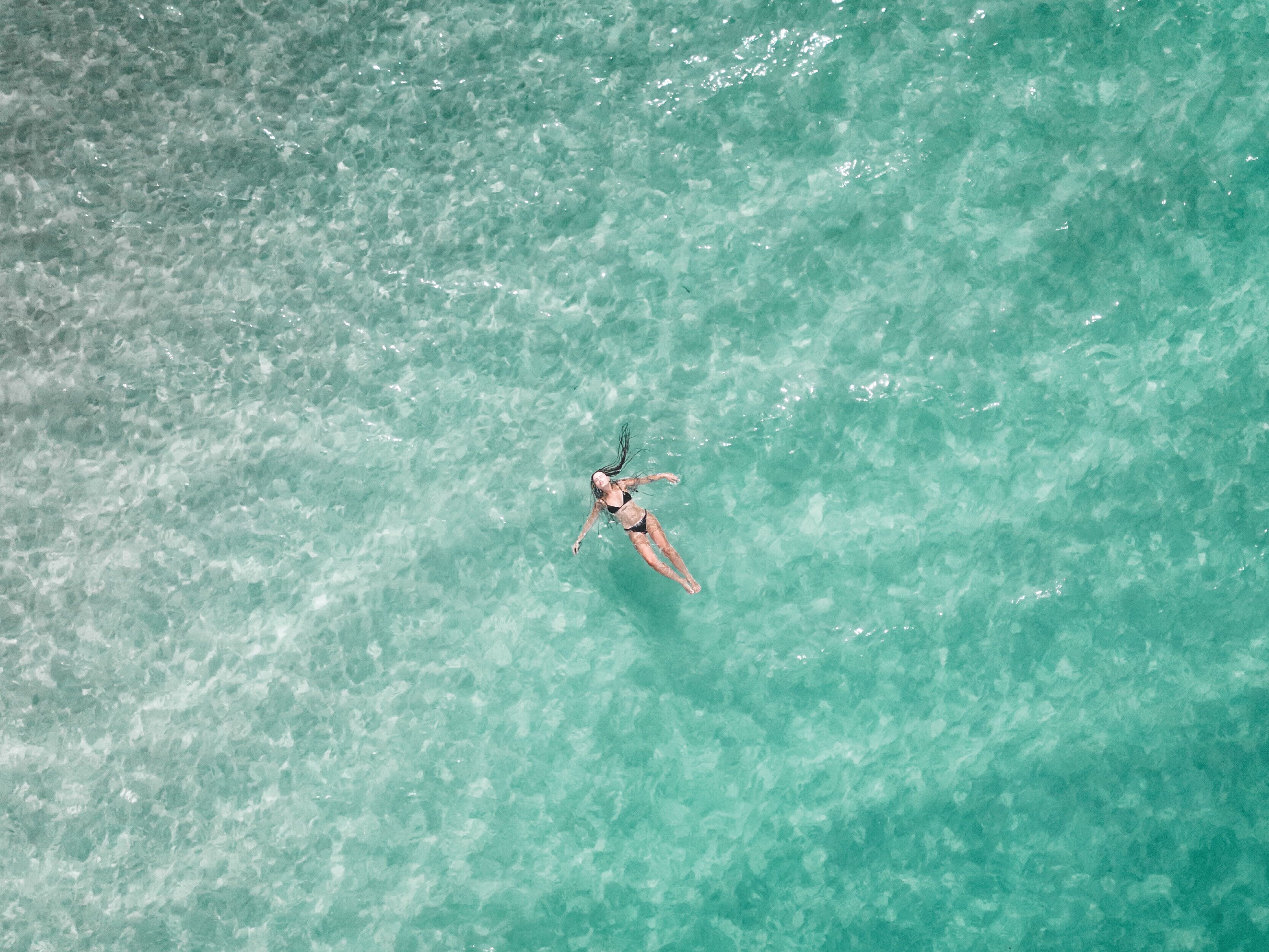 Une personne flottant dans une eau turquoise et cristalline.