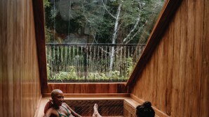 A wooden room with a sloped ceiling, a window, and a metal grid floor. - Palmar Beach Lodge (Bastimentos)
