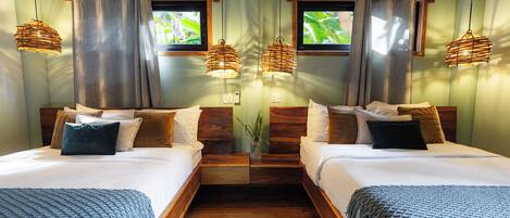 A room with two beds, wooden flooring, and hanging wicker lamps.