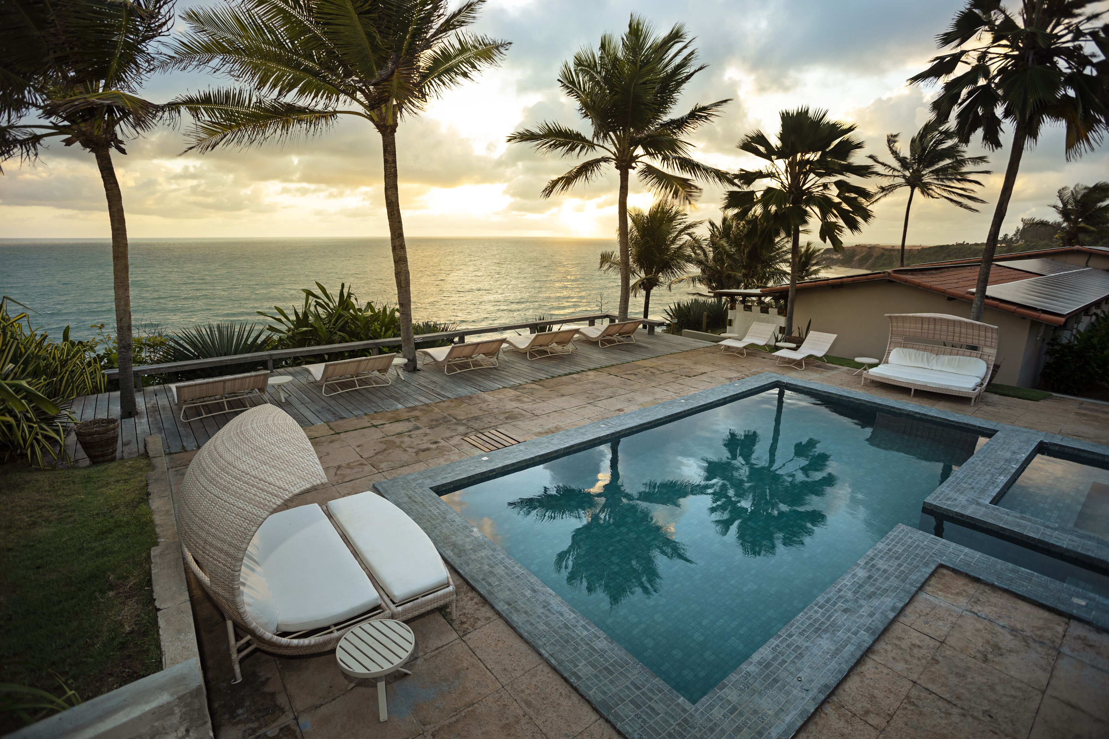 Un espace piscine avec des chaises longues et vue sur l’océan.