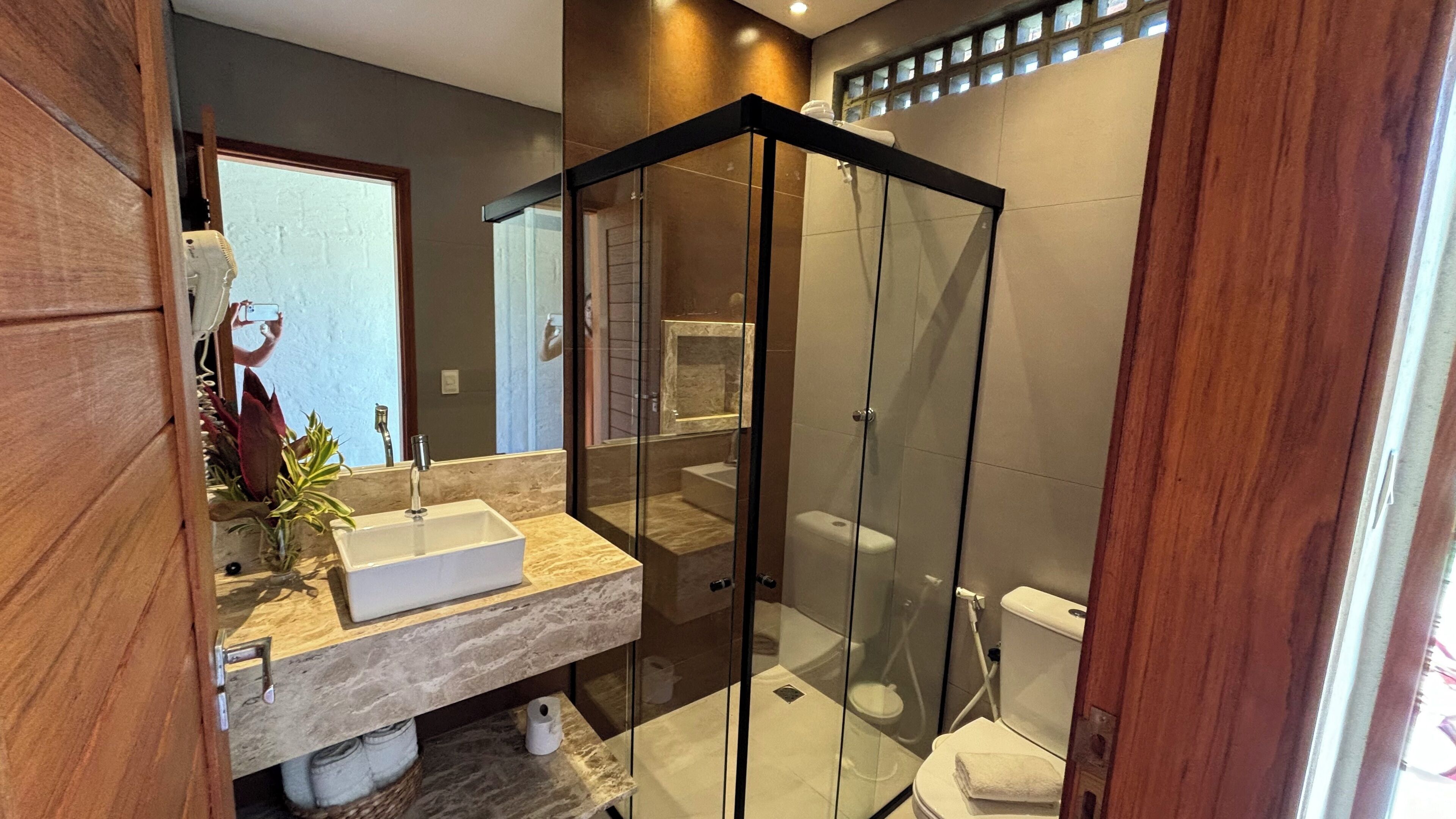 A modern bathroom with a glass-enclosed shower, a marble sink, and a visible toilet.