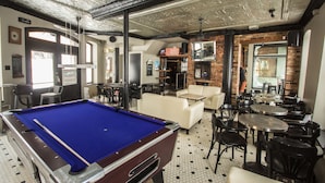 A pool table, seating area, and brick walls in a room. - Hotel Belley (Québec City)