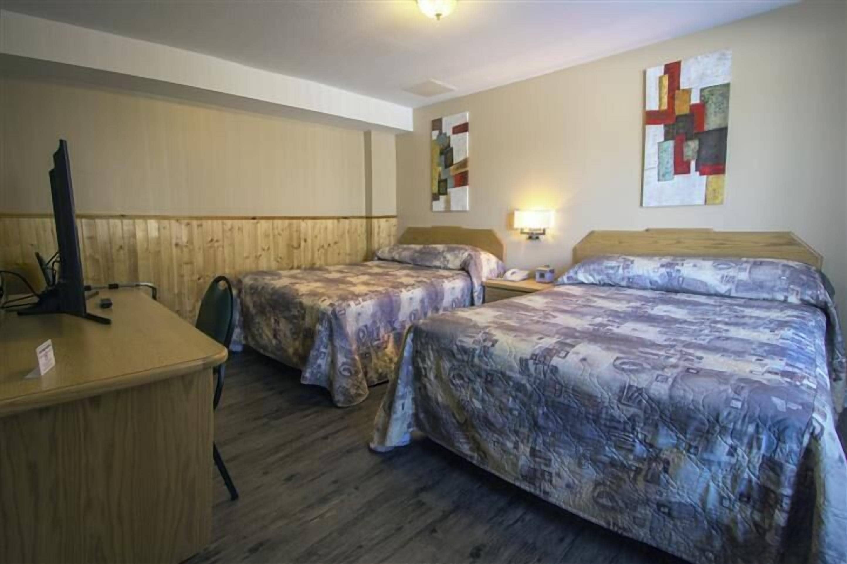 Habitación de hotel con dos camas individuales, un escritorio y una silla.