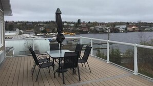 Una terraza con mesa y sillas, con vistas a un cuerpo de agua y un pueblo.