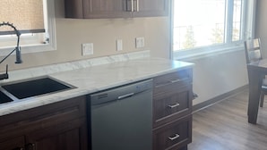 Una cocina con armarios de madera oscura, lavavajillas integrado y un amplio ventanal que proporciona luz natural.