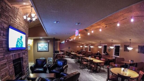 Un restaurante con asientos de cuero, un televisor montado en la pared y luces colgantes en el techo.