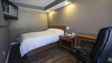 Habitación de hotel pequeña con una cama individual, un escritorio y una silla.