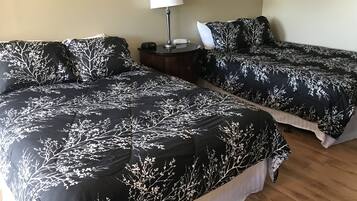 Et hotelværelse med to senge, et natbord med en lampe og et billede i ramme på væggen.