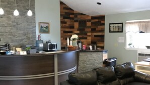 Un área de recepción con un mostrador curvo, un sofá de cuero negro y una pared con diseño de paneles de madera.