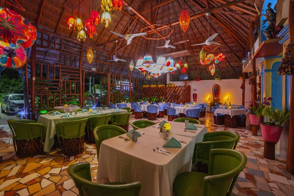Un restaurant doté de nombreuses tables et chaises, d’un sol carrelé et de décorations suspendues.