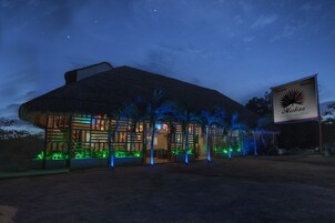 A large, thatched-roof building with a sign reading "Mestizo Guesthouse Hotel."