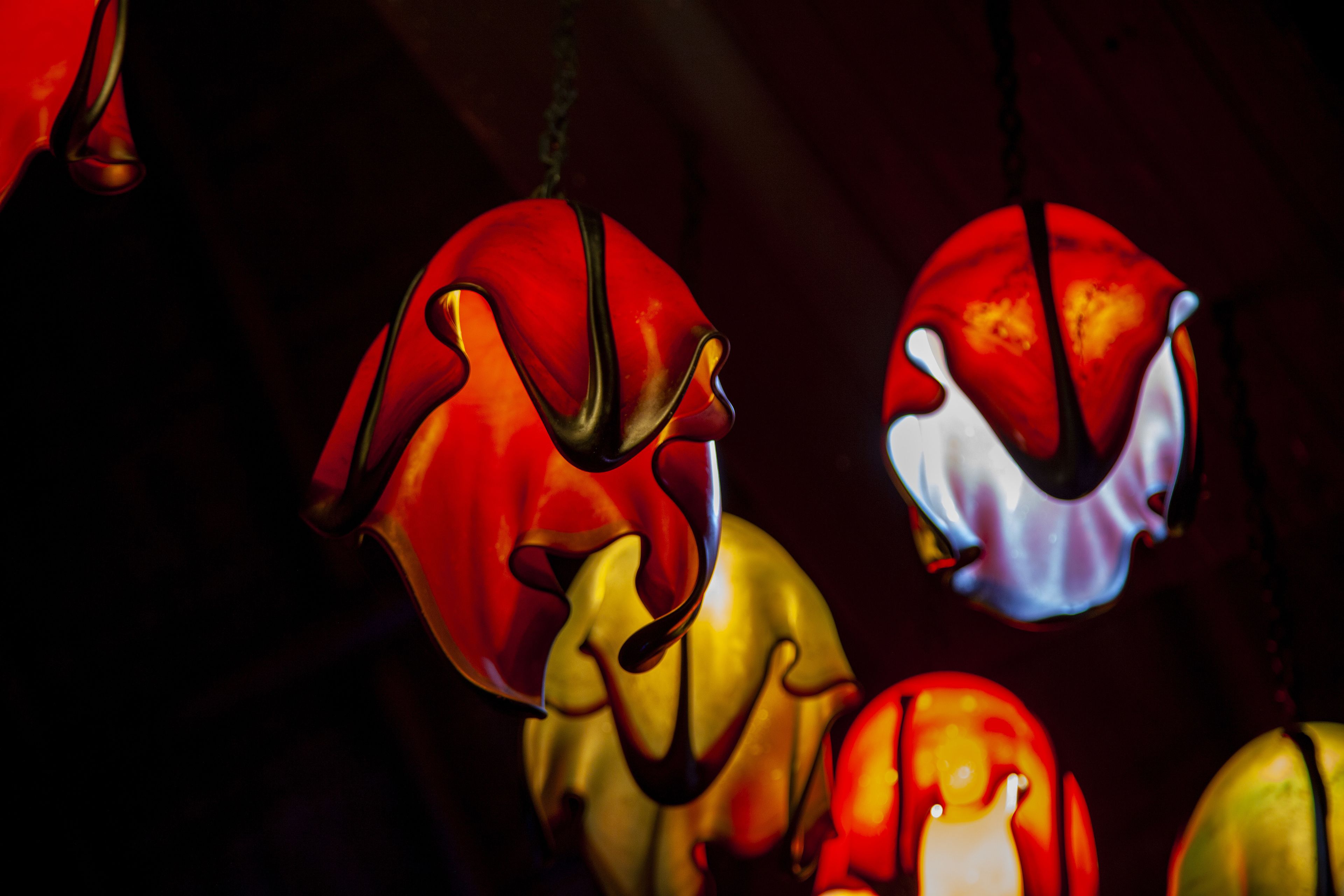 A close-up of a chandelier with multiple glass bulbs in red, yellow, and white colors.