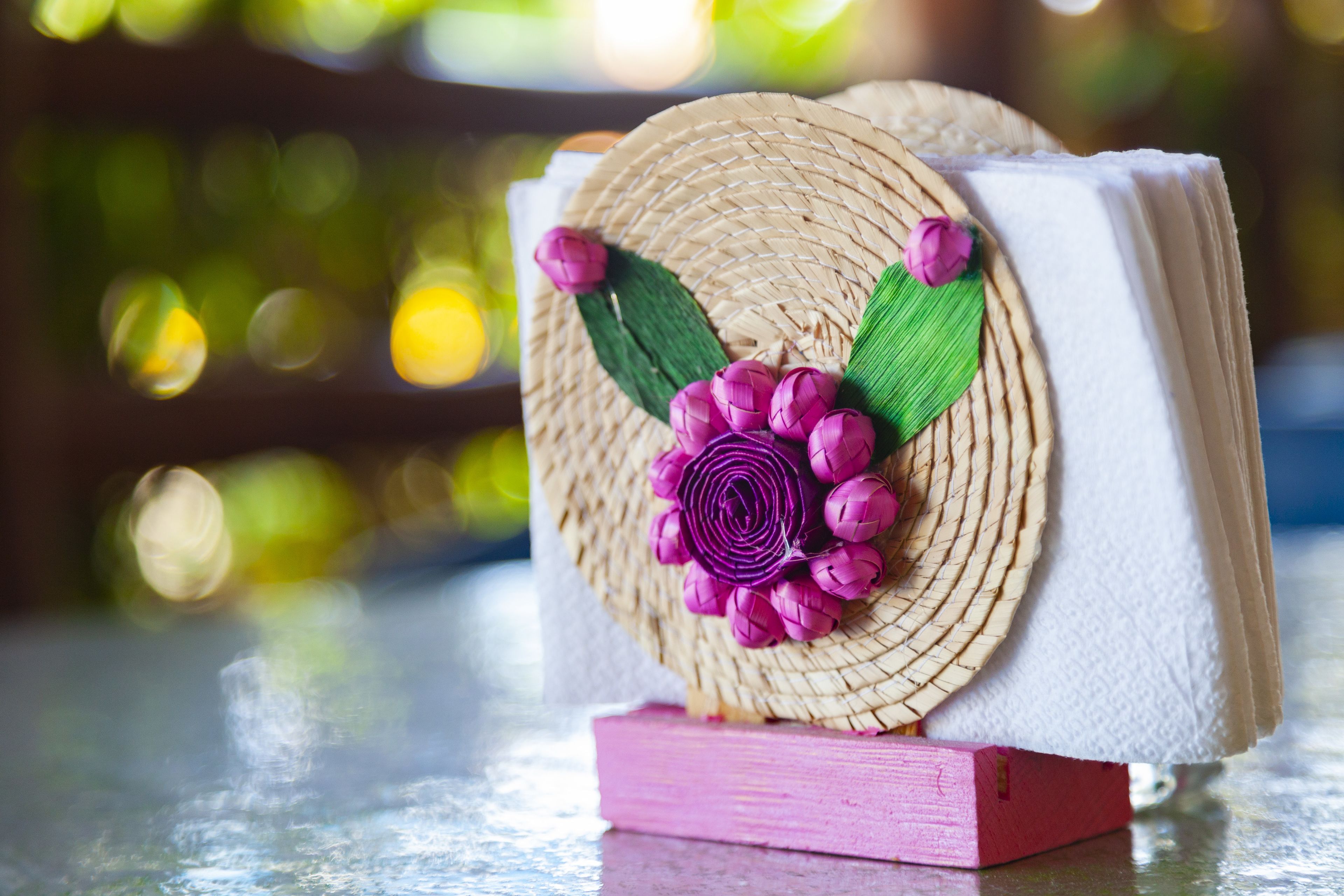 Uma cesta trançada com uma flor roxa sobre um livro rosa.