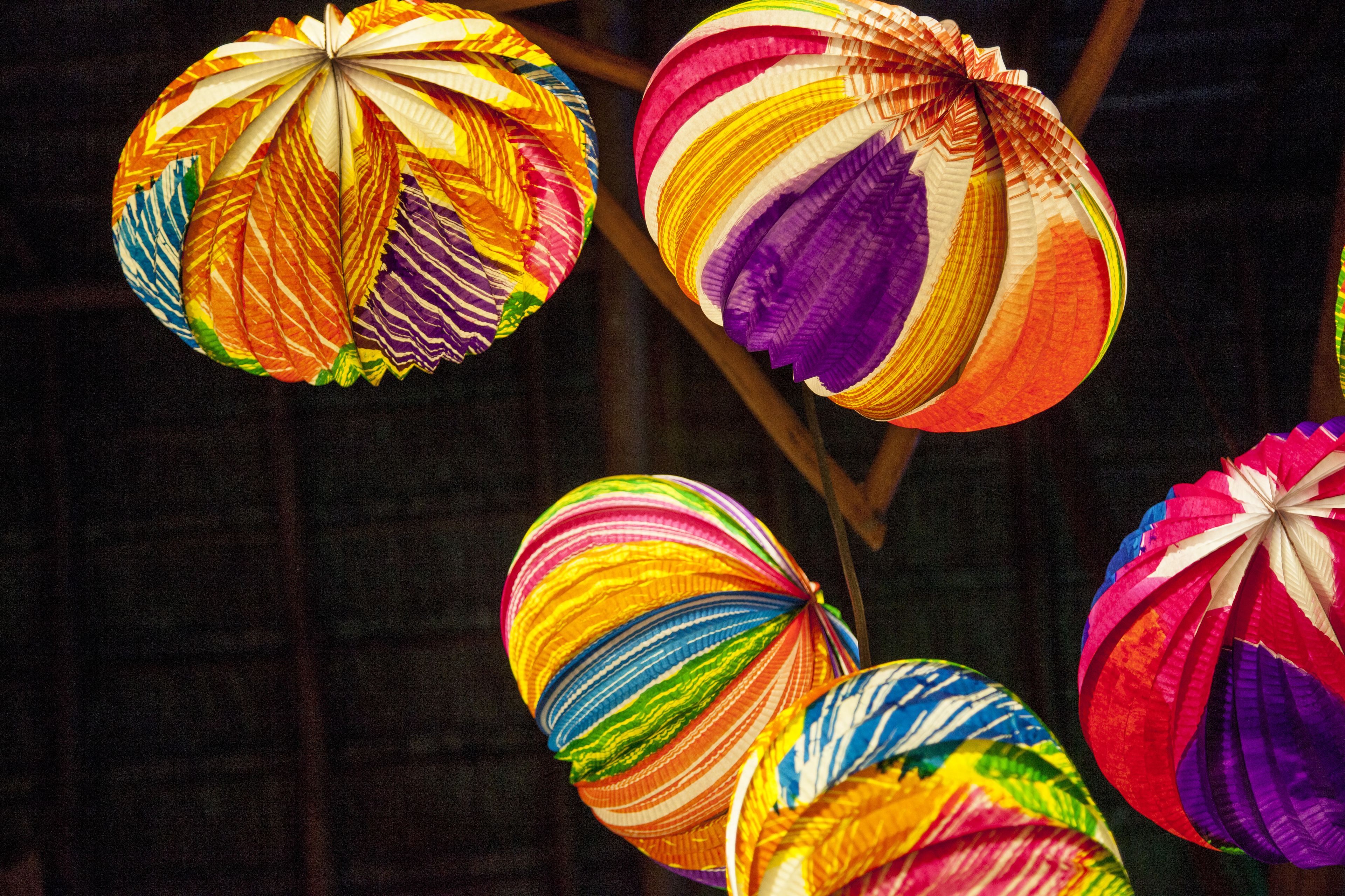 Een verzameling kleurrijke lampionnen hangt aan een constructie.