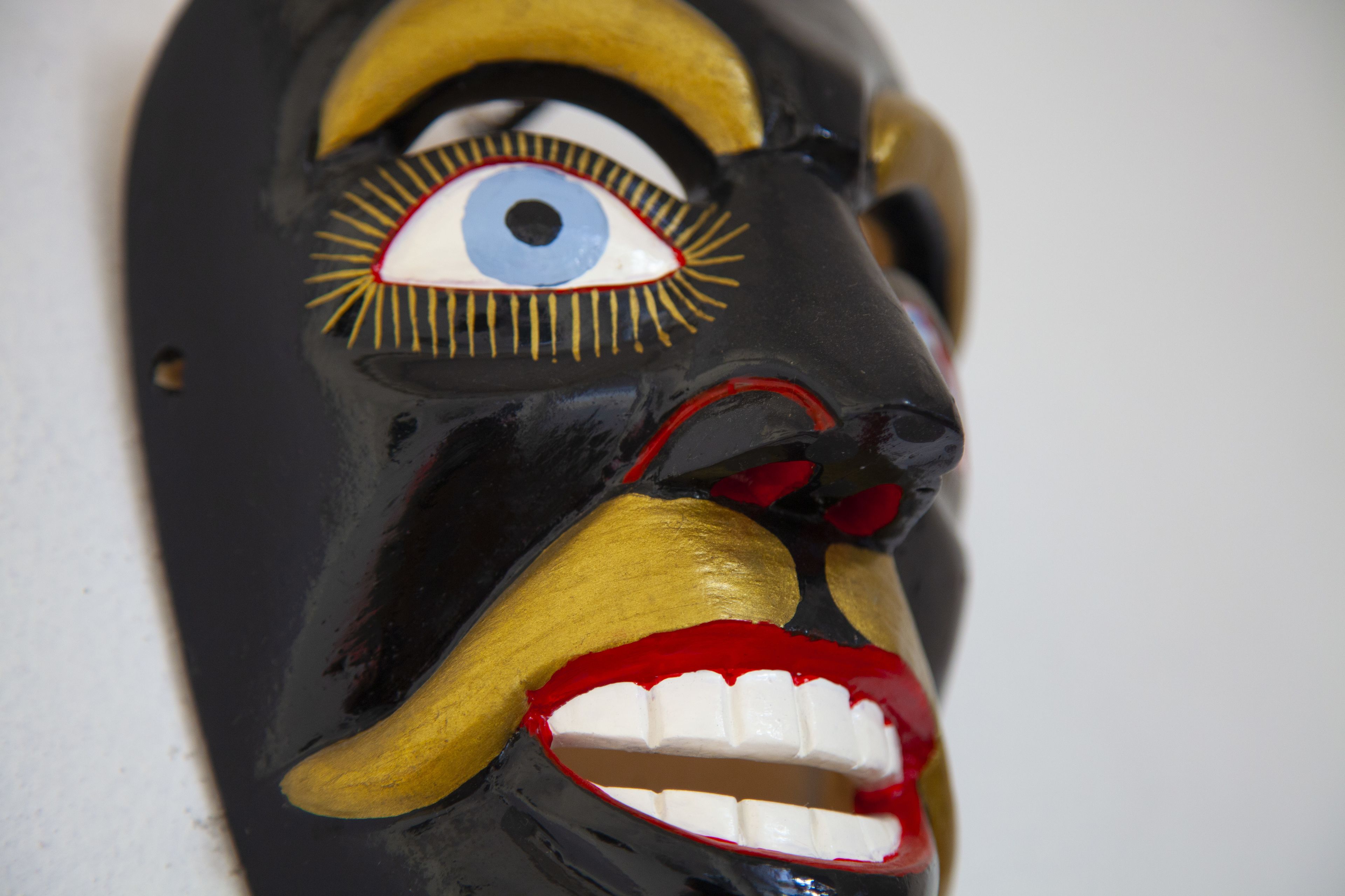 Un gros plan d’un masque dont les yeux et les dents sont particulièrement marqués.