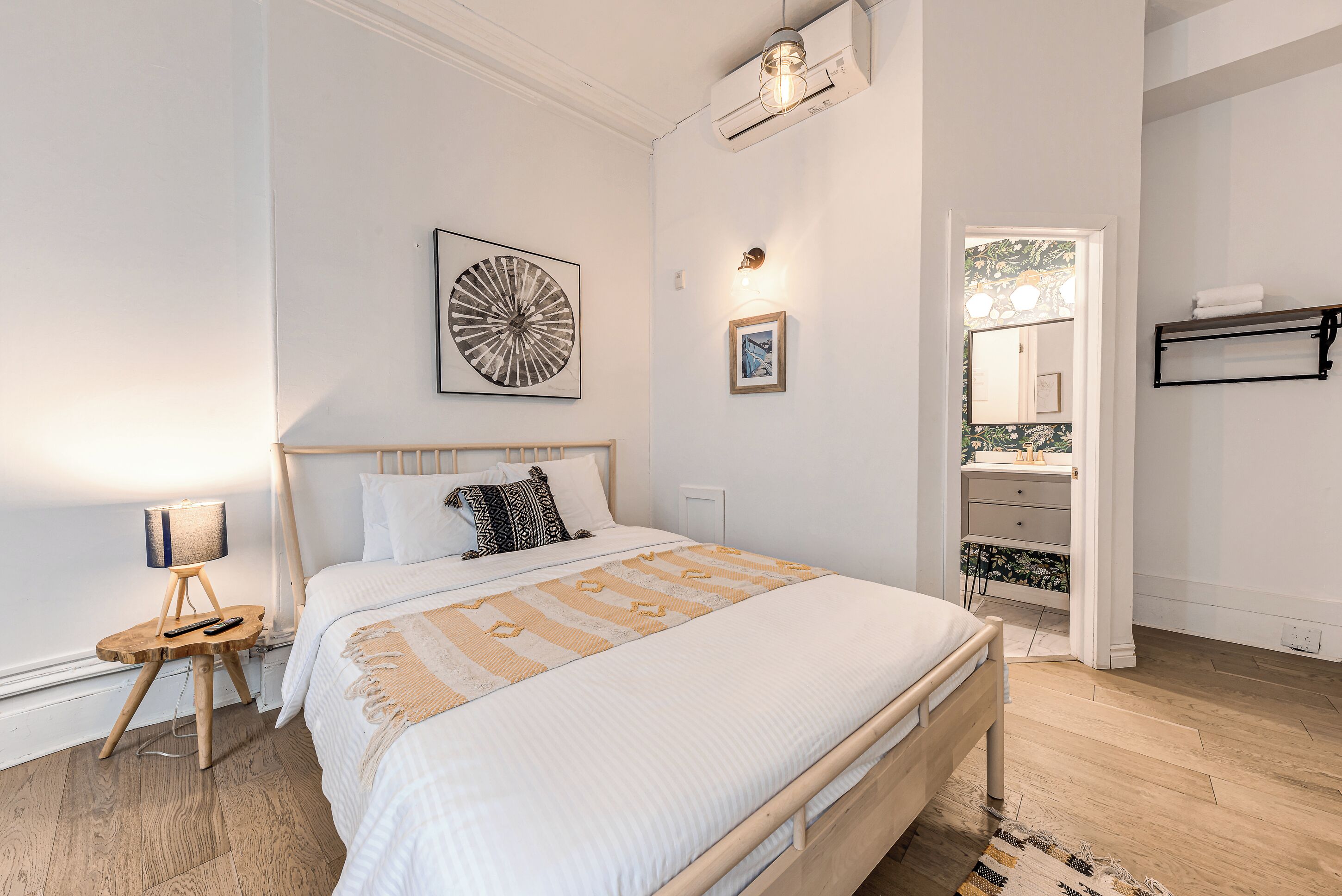 A bedroom with a bed, bedside table, lamp, and artwork.