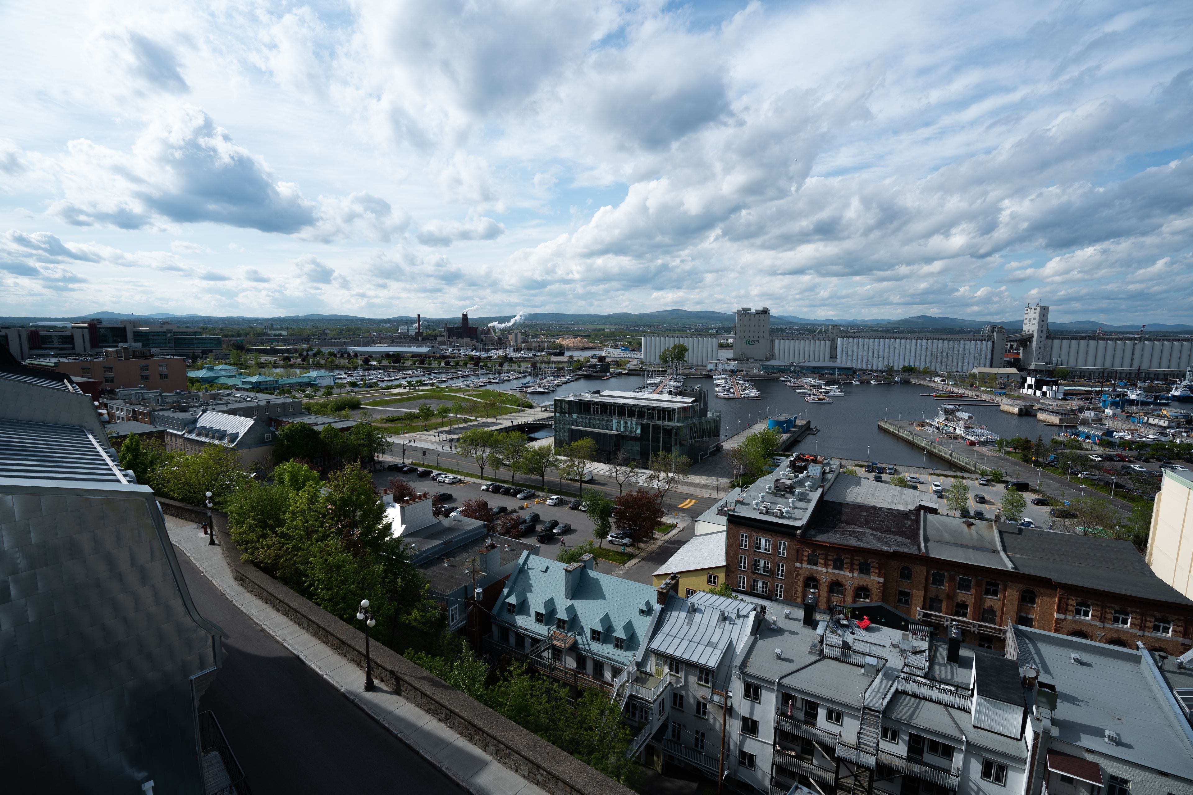 A cityscape with a mix of modern and traditional buildings, a marina with boats, and a large bridge in the distance.