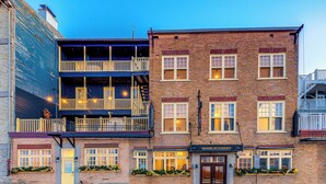 A two-story building with a ground-floor restaurant named "Manoir Des Remparts." The building features a brick facade, multiple windows, and a balcony with a railing. - North House - Manoir des Remparts / Hotel Automatisé (Québec City)