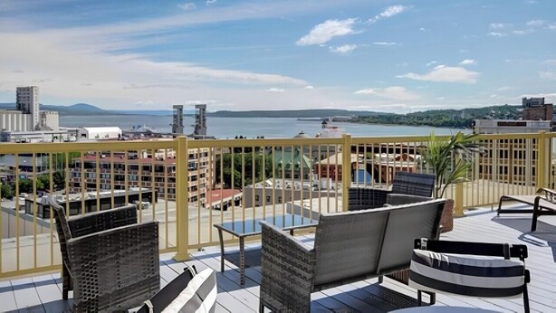 A rooftop terrace with outdoor seating and a view of the city and water. - North House - Manoir des Remparts / Hotel Automatisé (Québec City)