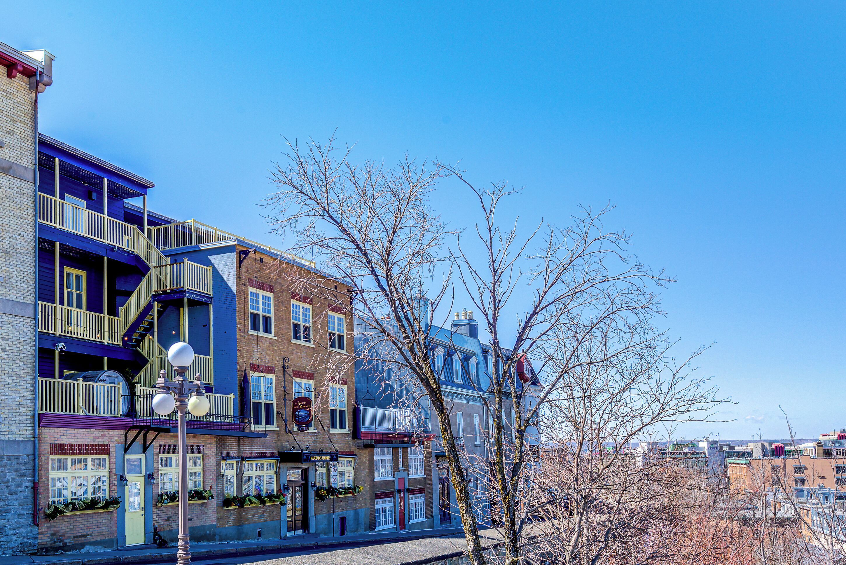 A multi-story building with balconies, a visible entrance, and a clear sky.