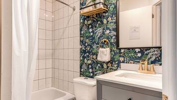A bathroom with a bathtub, toilet, and vanity with a mirror.