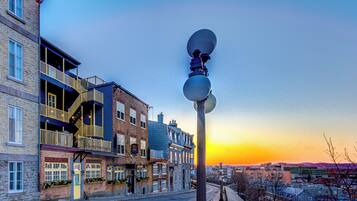 Una calle con edificios, un farol y una puesta de sol al fondo.