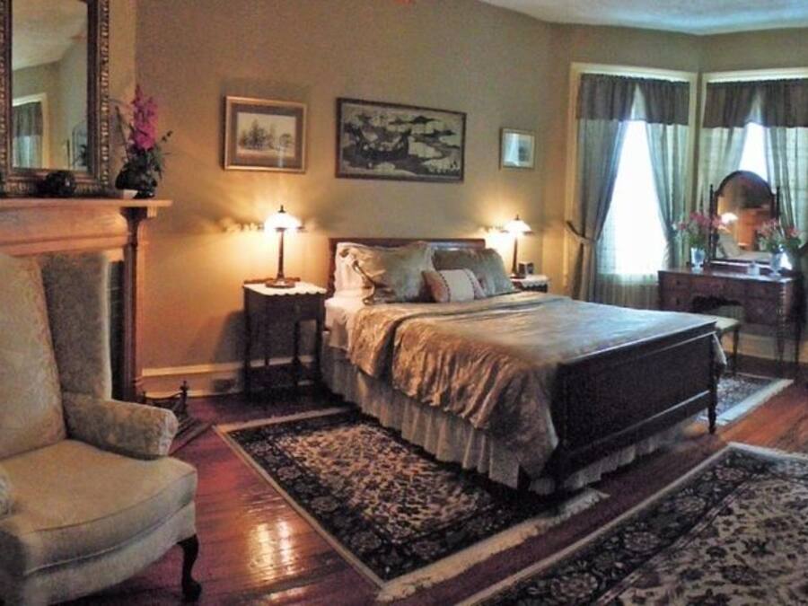 Um quarto com uma cama grande, duas mesas de cabeceira, uma cadeira e um penteado.