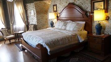 A classic bedroom with a wooden bed, two bedside tables with lamps, a chair, and a patterned rug.