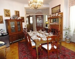 Comedor con una mesa de madera dispuesta para seis personas, rodeada de sillas. Encima de la mesa, un candelabro y a la izquierda, un aparador con puertas de cristal.