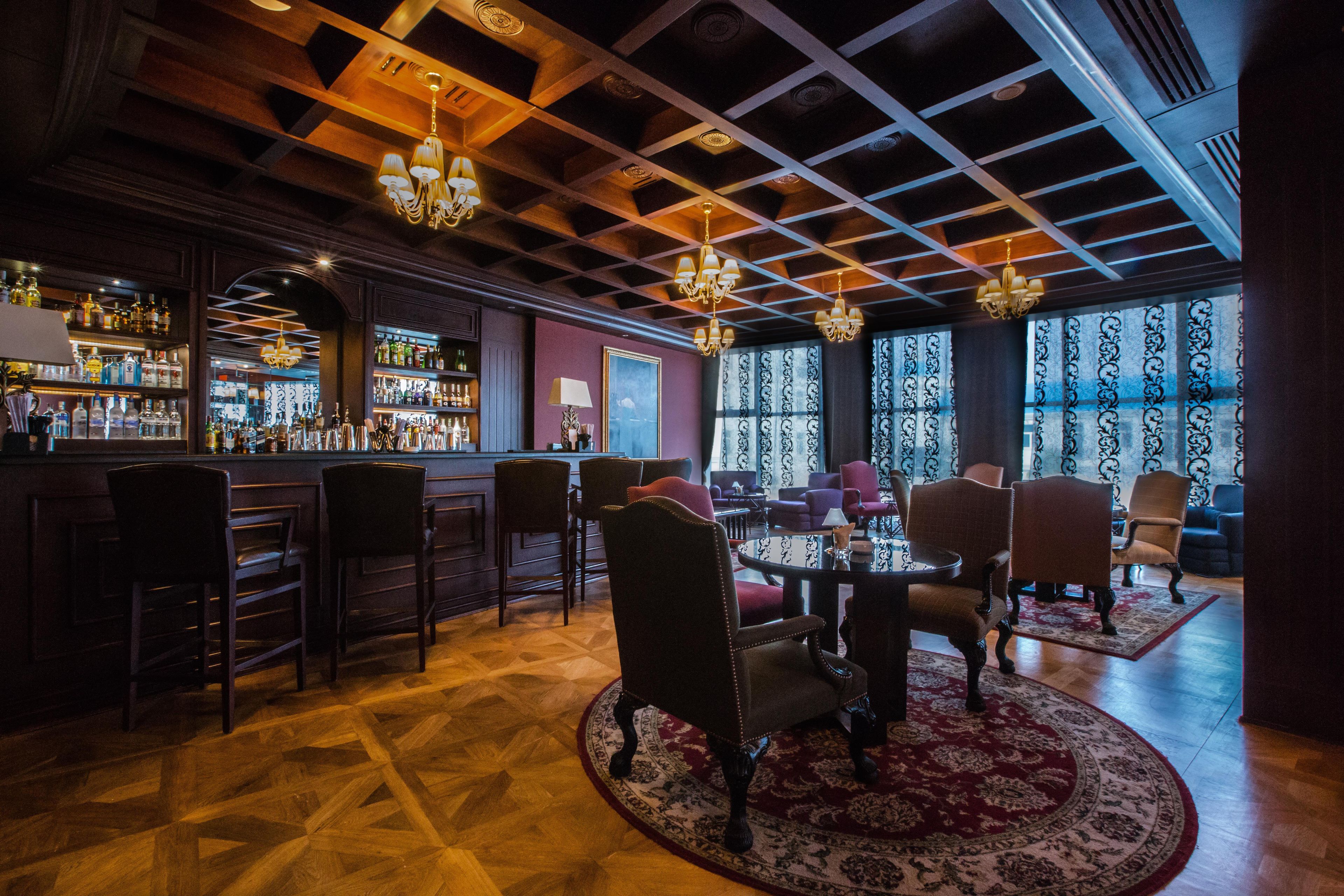 A bar area with wooden ceiling, bar stools, and a variety of bottles.